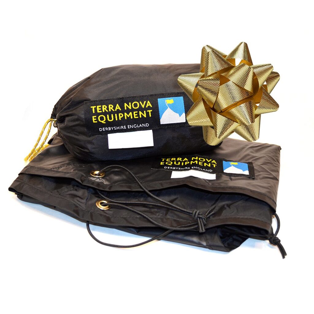 Folded black Terra Nova Equipment groundsheet or tent with matching stuff sack showing the blue-and-yellow logo, drawcord and grommets visible, topped with a large gold decorative bow