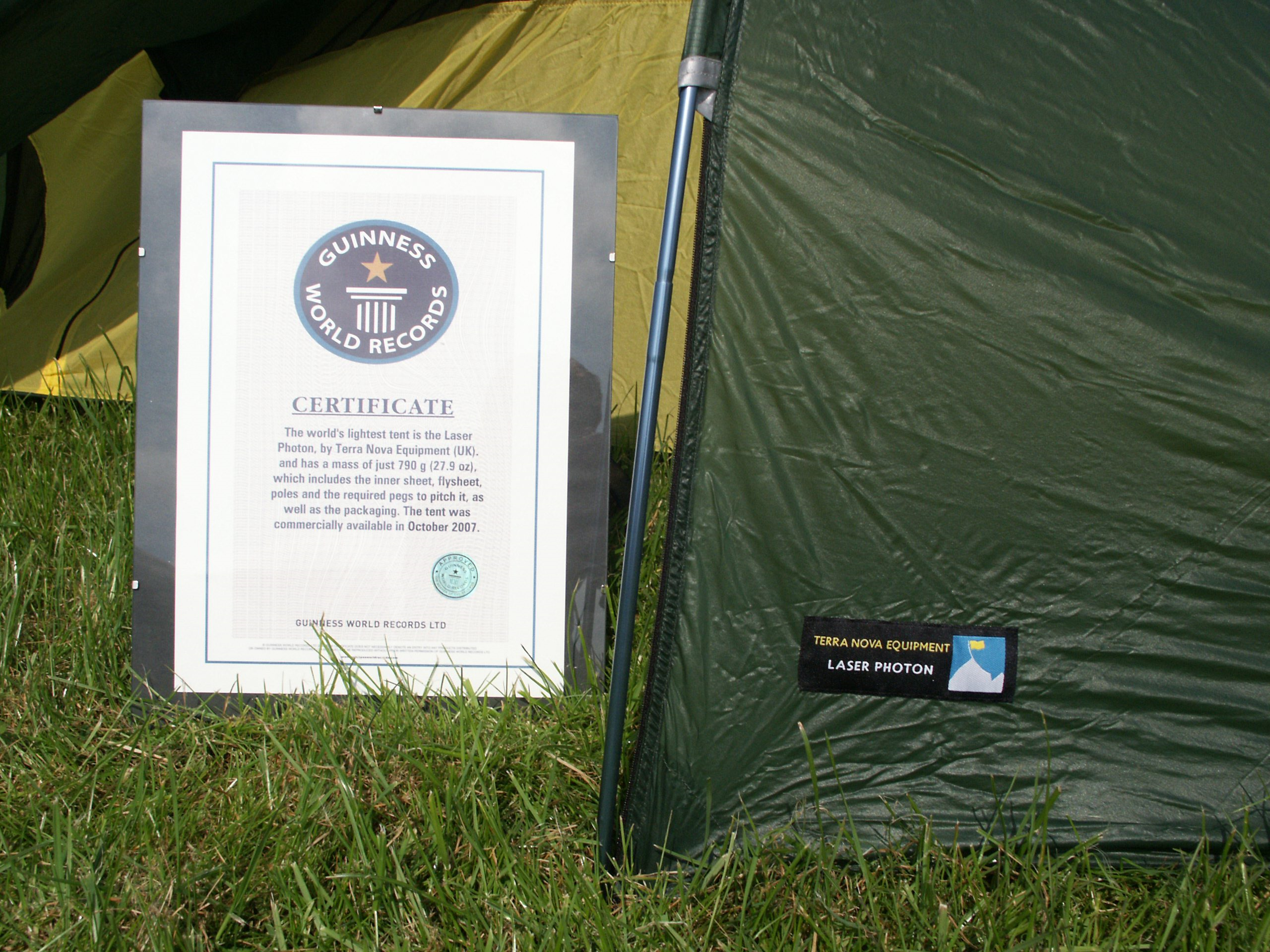 Guinness World Records certificate propped on grass next to the green side of a Terra Nova Laser Photon tent, with the circular Guinness logo and the tent's label visible.