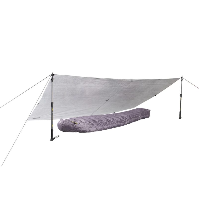 43TU1-Ultra-tarp-1-with-sleeping-bag-sqaure-3.jpg Silver emergency tarp pitched as a low shelter using two adjustable trekking poles and guylines, covering a purple mummy-style sleeping bag beneath.