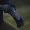 Close-up of a person wearing high-performance outdoor gloves, adjusting the cuff. The gloves feature a durable, weather-resistant design suitable for various outdoor activities.