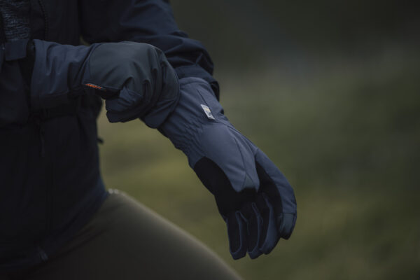 Close-up of a person wearing high-performance outdoor gloves, adjusting the cuff. The gloves feature a durable, weather-resistant design suitable for various outdoor activities.