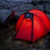 Blizzard-2-web-1.jpg Red dome tent glowing from an interior light, pitched on frosty ground among large weathered rocks at dusk.