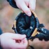 Capitol_Peak_LS-9-scaled-4.jpg Hands holding open a tan-and-black winter glove to reveal its soft black fur-lined interior against a blurred outdoor background.