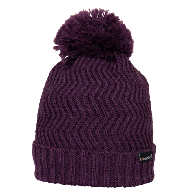 Castleton-Beanie-Foxglove-Cut-Out-300dpi-1.jpg Deep purple knitted beanie with a large fluffy pom-pom, chevron zigzag stitch pattern, ribbed folded cuff and small black brand label on the brim.