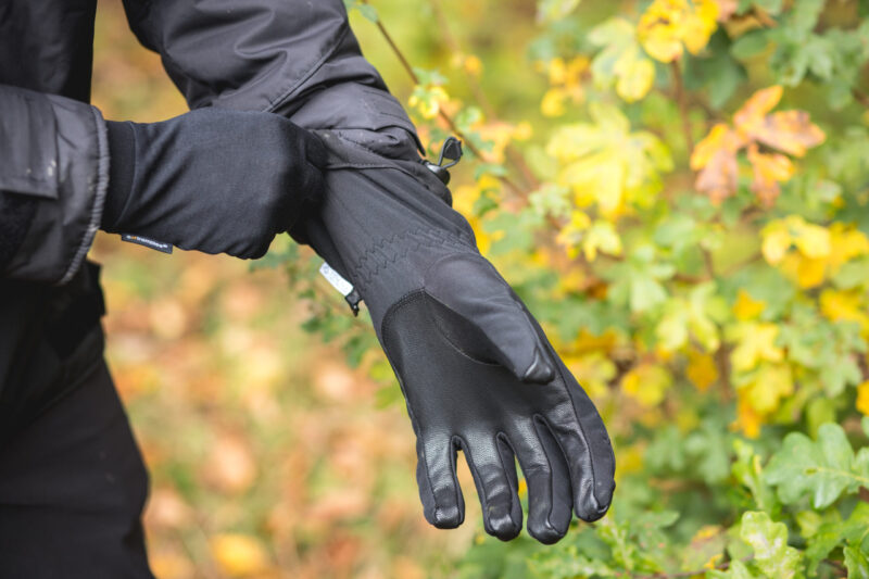 Extremitieshoot_Oct2019-157 (1) Black gardening gloves being worn by a person, with colorful foliage in the background, showcasing durability and grip for outdoor tasks.