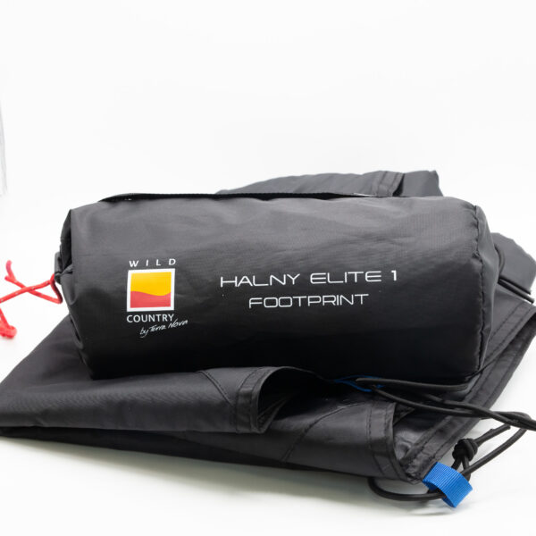 Halny-Elite-1-2-3.jpg Black rolled tent footprint in its storage bag labeled "HALNY ELITE 1 FOOTPRINT" with a yellow‑red Wild Country logo, red drawcord and blue tab, lying on a folded black groundsheet against a white background.