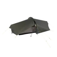 Low-profile olive-green one-person backpacking tarp tent pitched using a trekking pole at the entrance, with a covered mesh inner and several yellow guylines staked out.