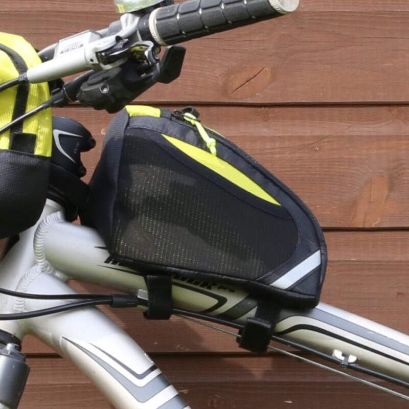 Black triangular top-tube bicycle frame bag with yellow accents strapped beneath the handlebars on a silver bike, shown against a wooden plank background.