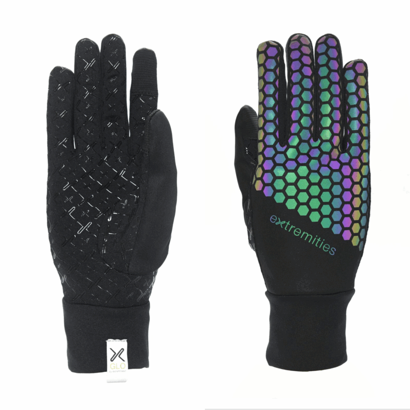 Two black gloves shown flat, one palm-side up with textured rubberised cross-grip and a white GLO cuff tag, the other back-side up with a multicoloured iridescent hexagonal pattern and 'extremities' logo.