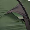 Close-up of a green ripstop tent fly and vented inner door with a black fabric hood supported by a curved pole and secured by a yellow guyline.