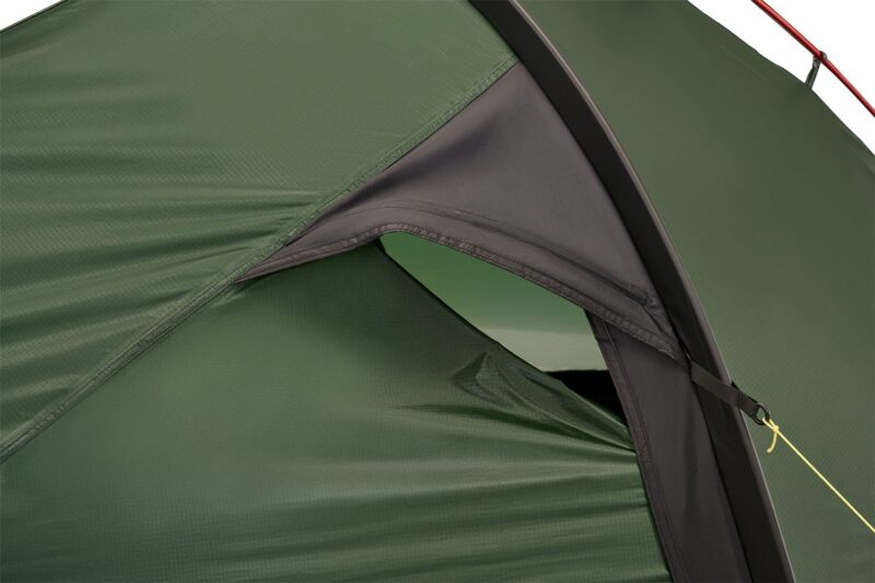 Close-up of a green ripstop tent fly and vented inner door with a black fabric hood supported by a curved pole and secured by a yellow guyline.
