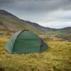 Southern-Cross-2-LR-3.jpg Green dome tent pitched on a grassy hillside with guy lines staked down, overlooking a broad valley and winding road between rugged mountains beneath a cloudy, overcast sky.