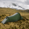 Starlite-1-23_LR-1.png A lone olive-green tunnel tent pitched on windswept brown grass amid rocky moorland, with low cloud and mist rolling over distant mountains under an overcast sky.