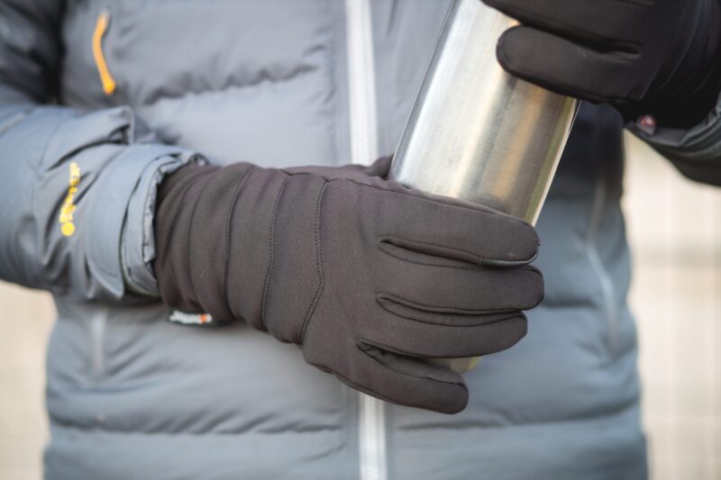Super-thicky-scaled-2.jpg Hands in black winter gloves holding a stainless-steel thermos in front of a grey padded jacket with a yellow zip detail.