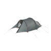 Low-profile grey two-person tunnel tent with a front vestibule and partially open inner door, supported by curved black poles and pegged guy lines with red and blue pole accents.