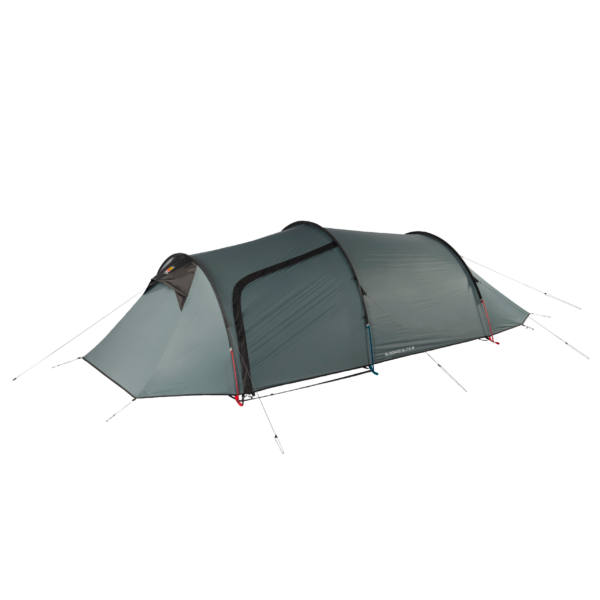 Green-grey, low-profile three-person tunnel tent with arched poles, a front vestibule and a zippered side door, secured with red and blue guy lines on a plain background.