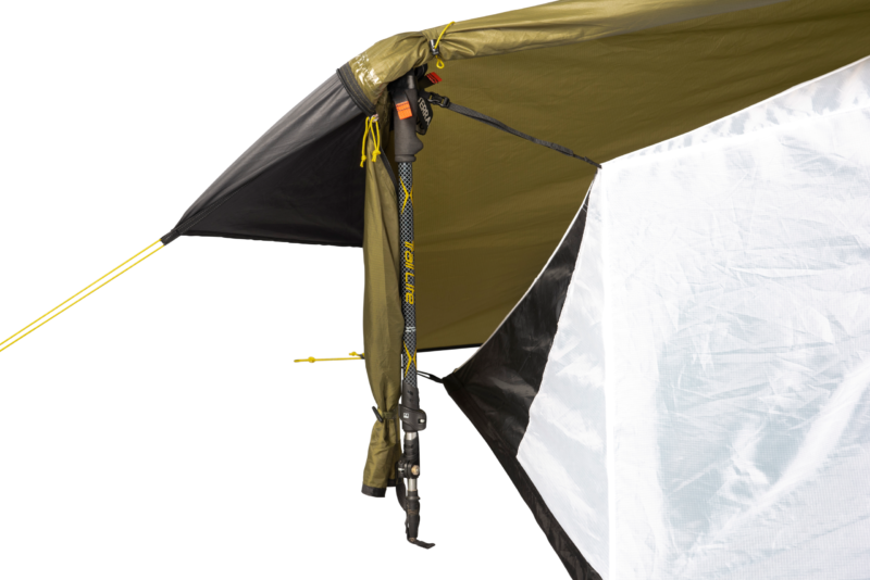 Close-up of a trekking pole used as a tent pole supporting an olive-green rainfly and white tent wall, with yellow guy lines, black straps and clips securing the fabric.