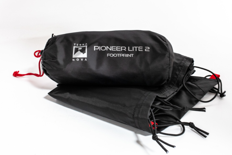 pioneer_lie_footprint__3-3.webp Compressed black stuff sack labelled 'Terra Nova PIONEER LITE 2 FOOTPRINT' with a red drawcord, resting beside folded black groundsheet fabric on a white background.
