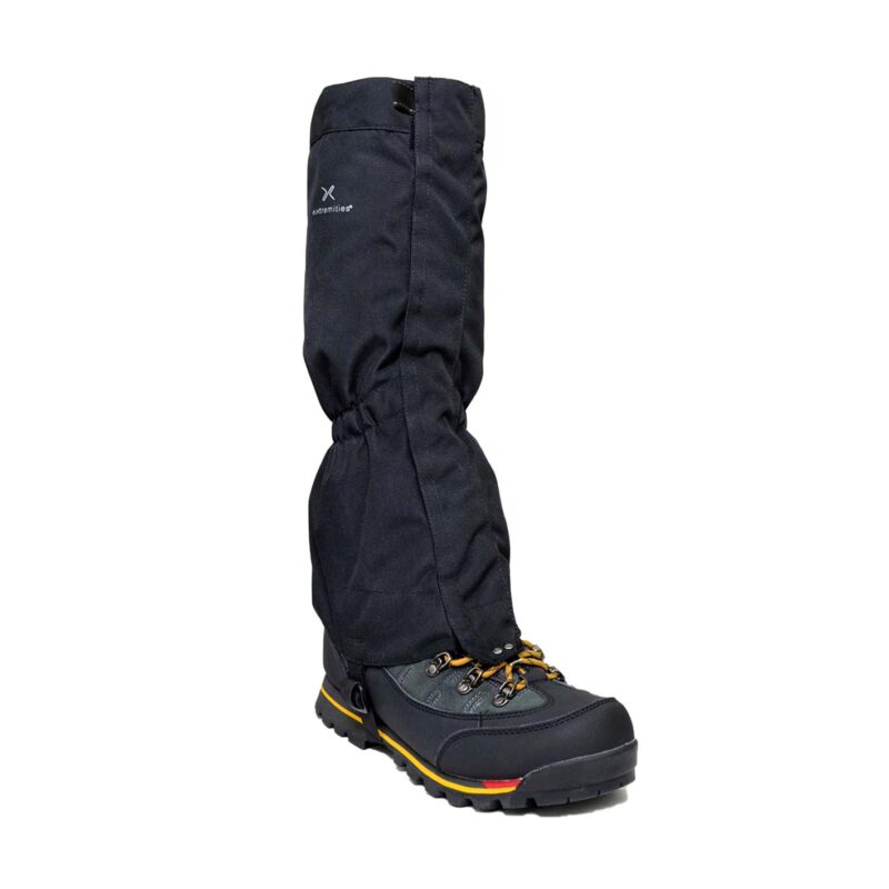 Black waterproof gaiter pulled over a black hiking boot with yellow laces and a yellow-and-red striped rugged sole, elasticated at the ankle and bearing a small 'Extremities' logo.