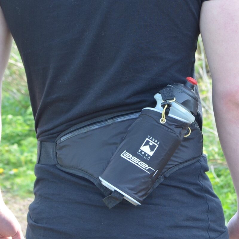 zoom_EOL_Laser_1_Pack-1.jpg Rear view of a person in a black T-shirt wearing a black waist pack with a side pocket holding a water bottle with a grey cap and red spout, against a green outdoor background.