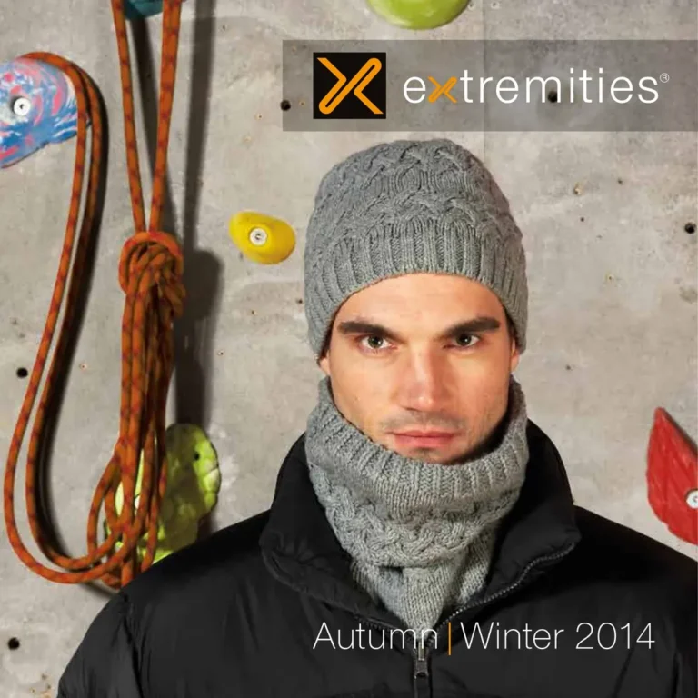Man wearing a gray knitted hat and matching scarf, posing against a climbing wall with climbing gear, showcasing Extremities Autumn/Winter 2014 collection.