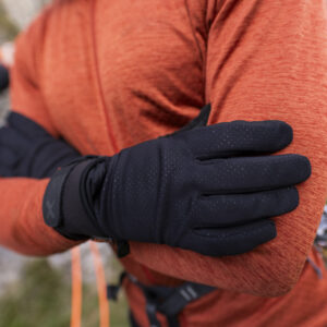 Close-up of a person wearing black gloves, with arms crossed, showcasing outdoor apparel in a rugged environment. Ideal for winter sports or climbing activities.